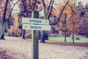 Rustic wooden sign in an autumn park with the words Afraid- Brave offering a choice of action and attitude with arrows pointing in opposite directions in a conceptual image.